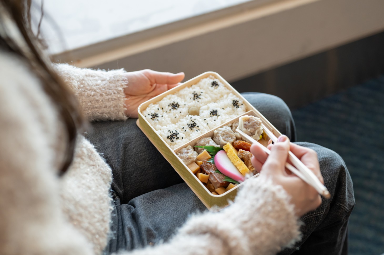 A woman eating an Ekiben on the train.