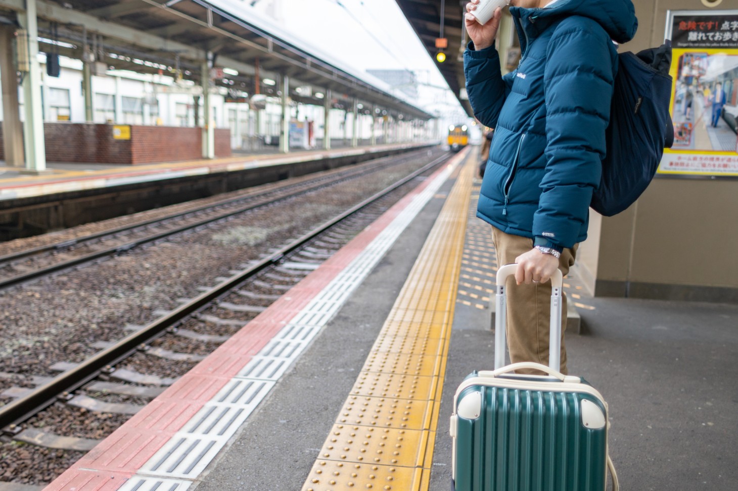 A traveler drinking coffee on the platform.